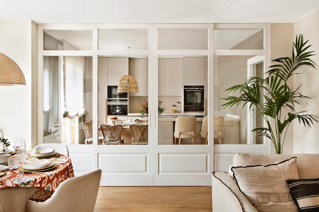 Imagen de reforma integral en Damas, Madrid, con una cocina y salón. Llama la atención un cerramiento en madera y cristal que separa ambas estancias.